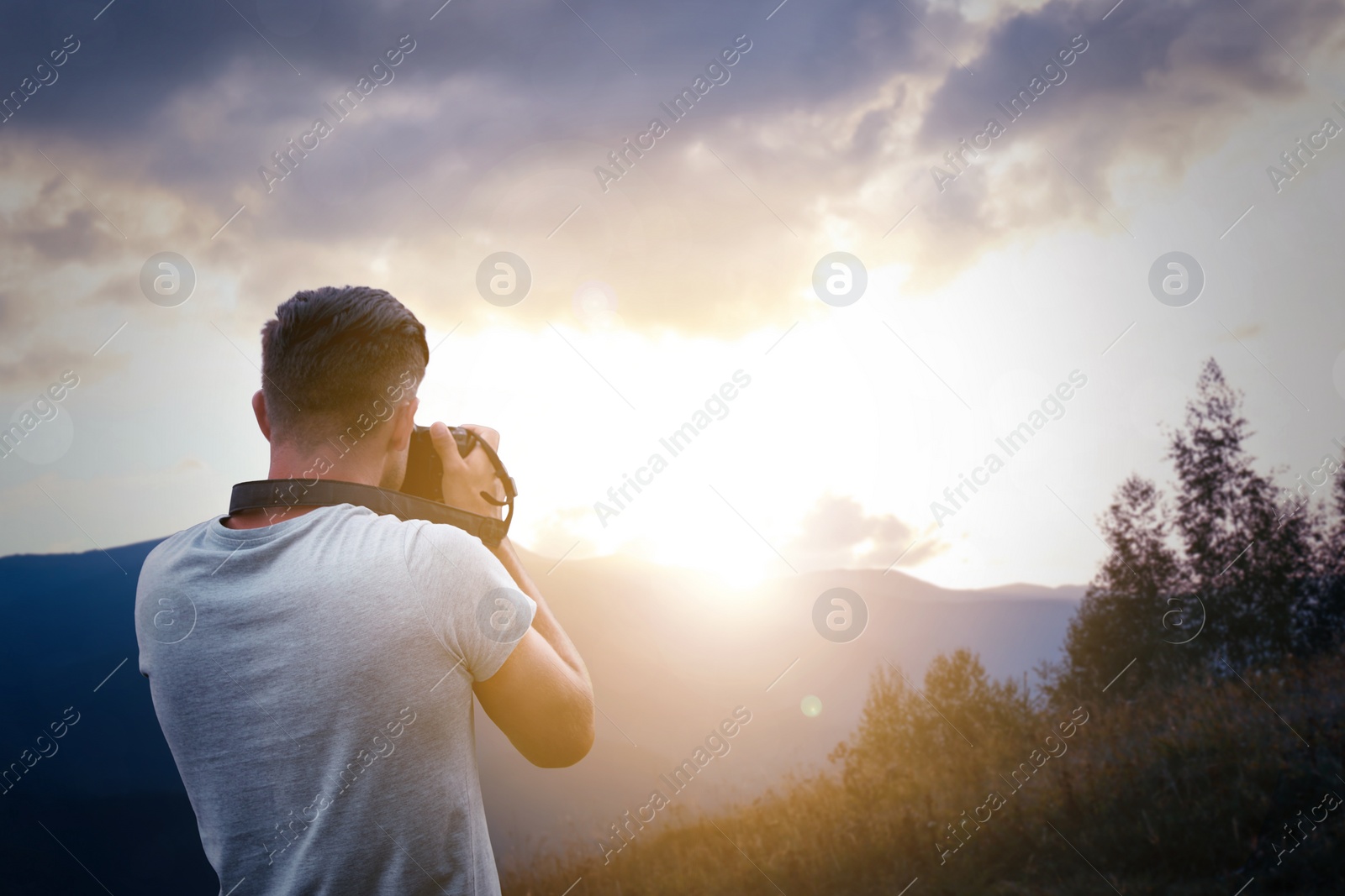 Image of Photographer taking picture of beautiful mountains at sunrise with professional camera