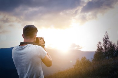 Image of Photographer taking picture of beautiful mountains at sunrise with professional camera