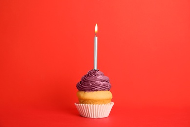 Birthday cupcake with candle on red background