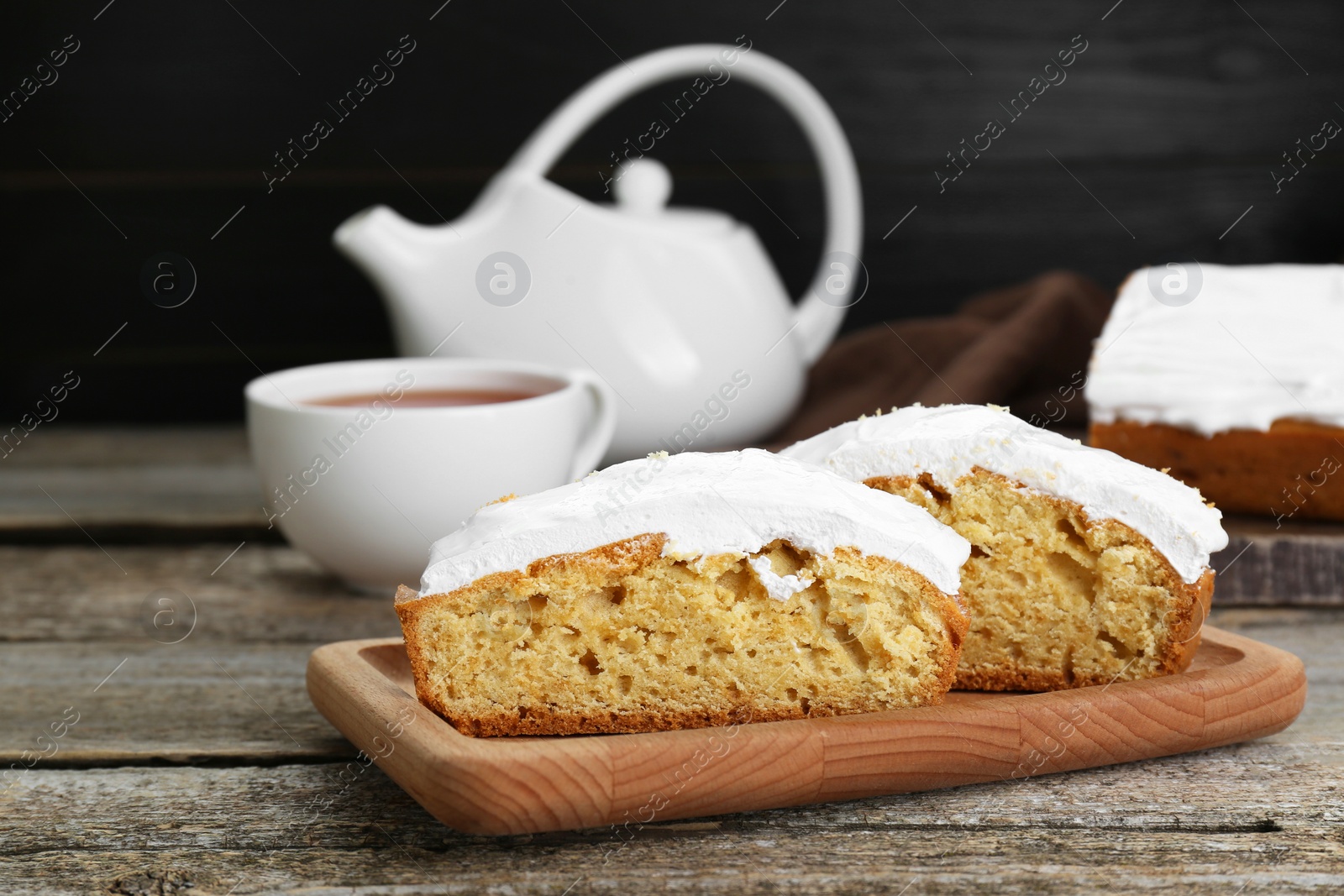 Photo of Pieces of homemade yogurt cake with cream on wooden table