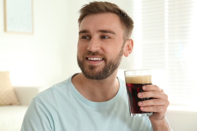 Handsome man with cold kvass indoors. Traditional Russian summer drink