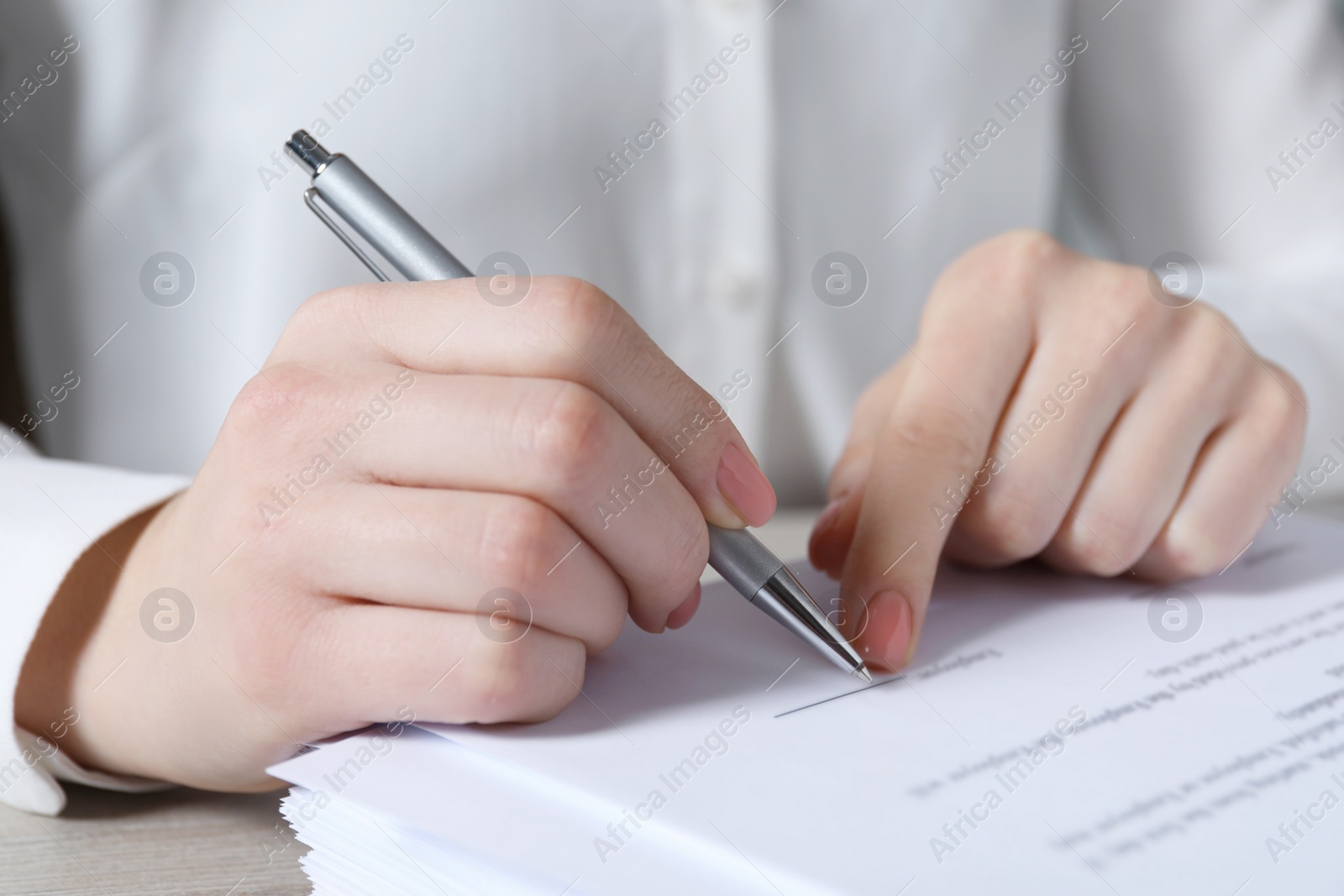 Photo of Woman signing document at table in office, closeup