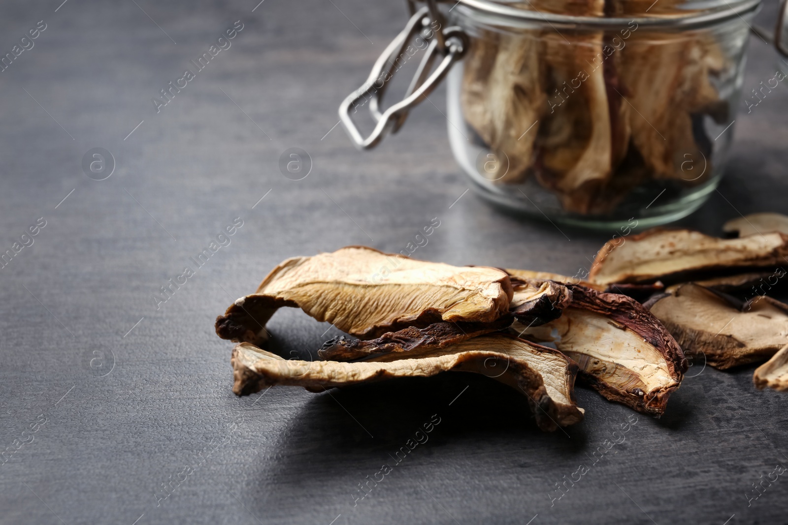 Photo of Composition of dried mushrooms and glass jar on table, closeup