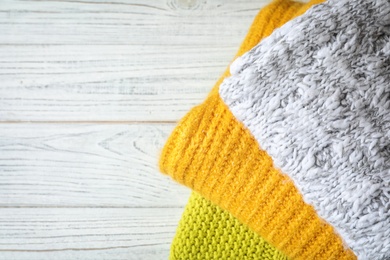 Photo of Stack of warm knitted clothes on wooden table