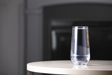 Photo of Glass of clean water on white table indoors, space for text
