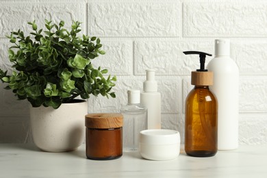 Photo of Bath accessories. Personal care products on white table near brick wall