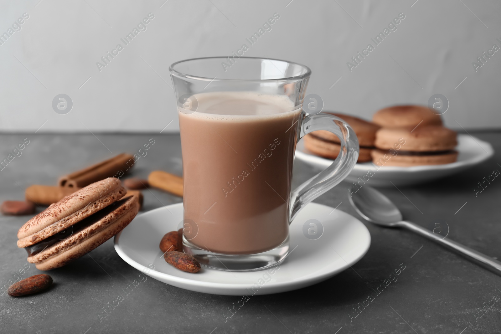 Photo of Glass cup with tasty hot cocoa drink and macaron on table