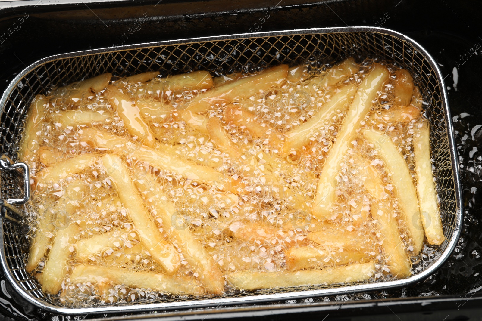 Photo of Cooking delicious french fries in hot oil, closeup