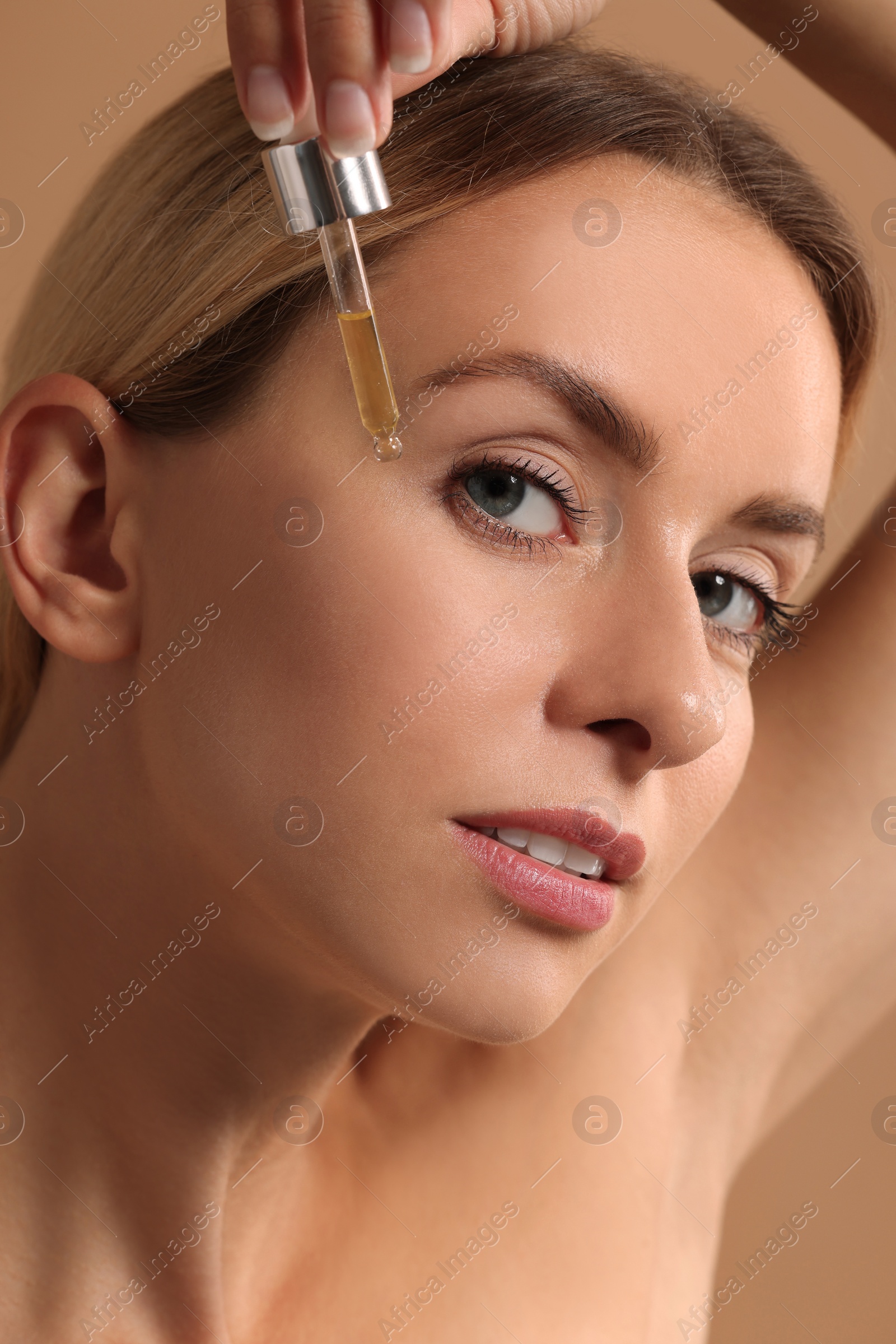 Photo of Beautiful woman applying cosmetic serum onto her face, closeup