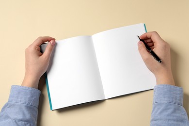 Photo of Man with pen and notepad on beige background, top view