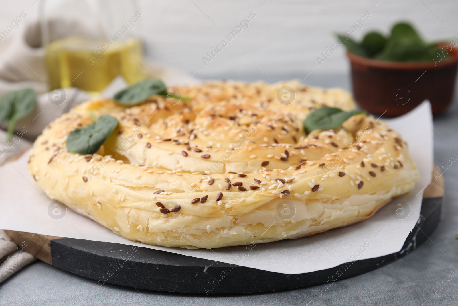 Photo of Delicious puff pastry with spinach on grey table, closeup