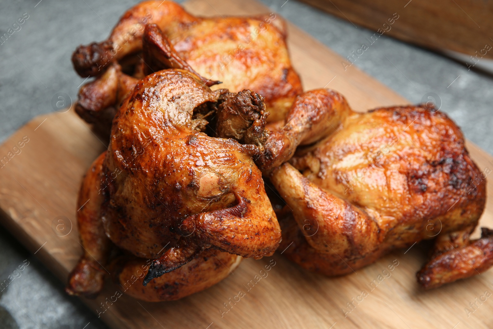 Photo of Delicious grilled whole chickens on grey table, closeup