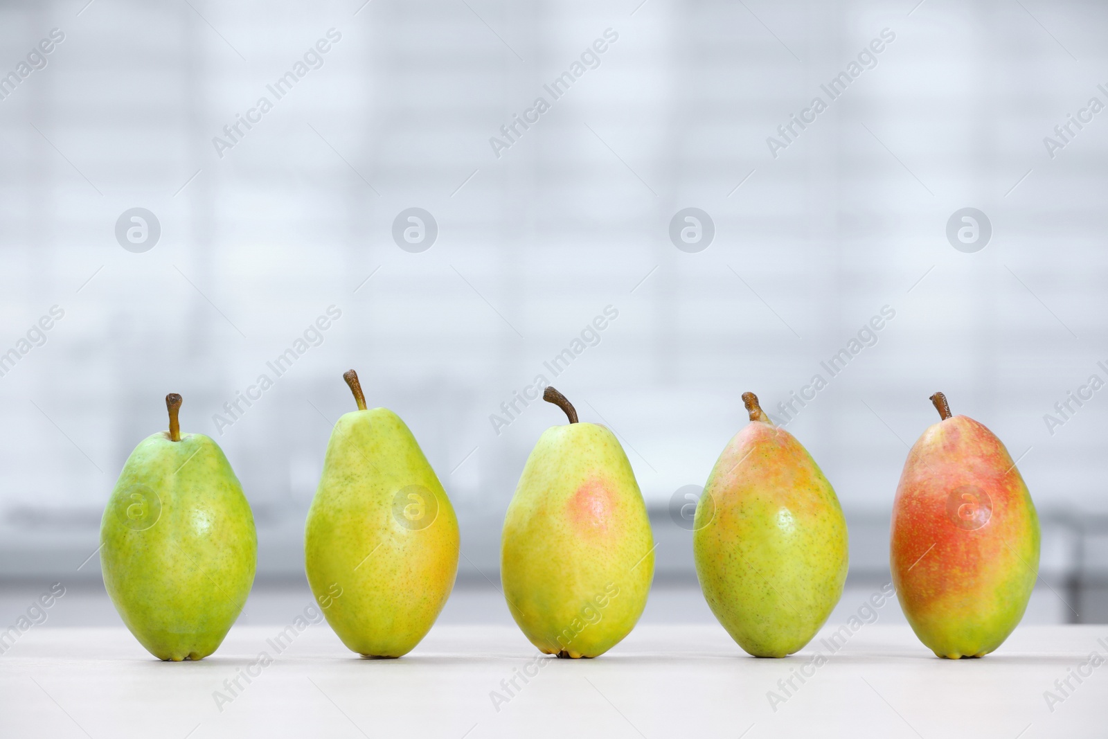 Photo of Fresh ripe pears on white table in kitchen. Space for text
