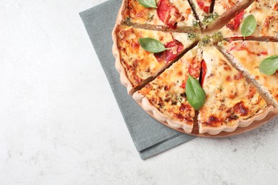 Photo of Tasty quiche with tomatoes, basil and cheese on light textured table, top view. Space for text