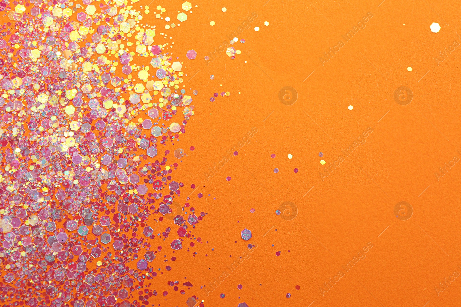 Photo of Shiny bright lilac glitter on orange background, flat lay. Space for text