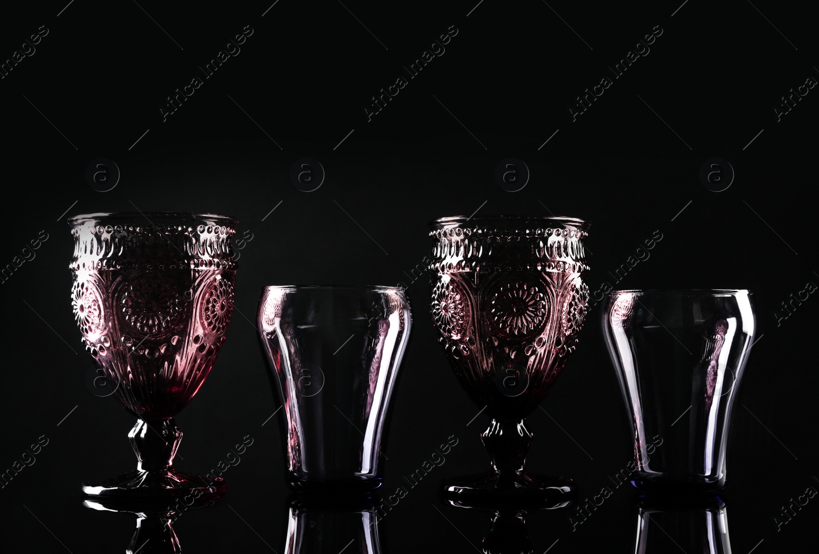 Photo of Set of different colorful empty glasses on black background