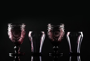 Set of different colorful empty glasses on black background