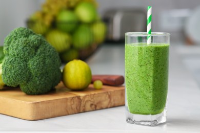 Glass of delicious smoothie and ingredients on white table in kitchen