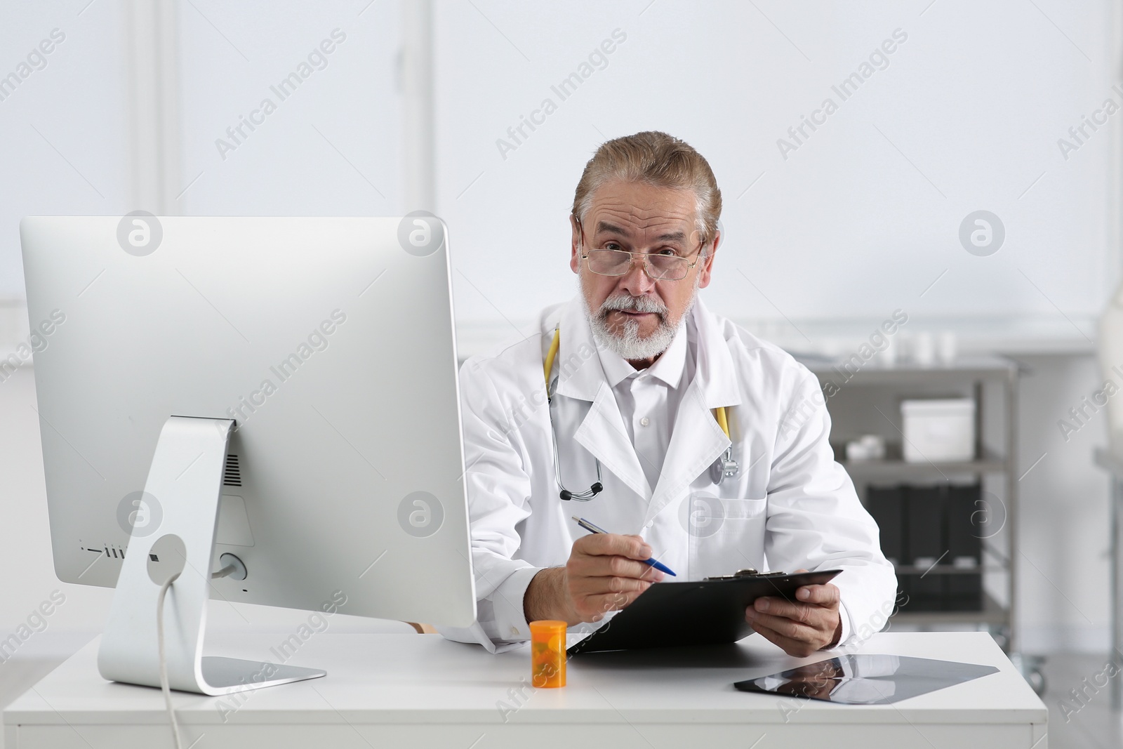 Photo of Doctor filling patient's medical card at table in clinic