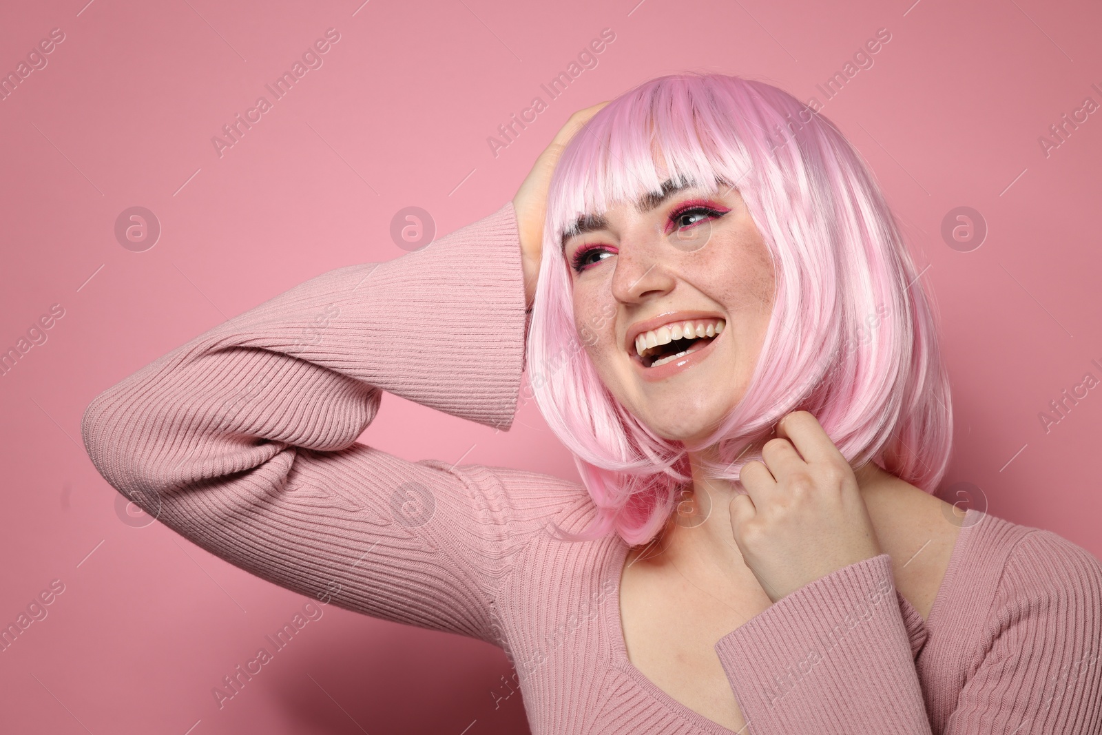 Photo of Happy woman with bright makeup and fake freckles on pink background