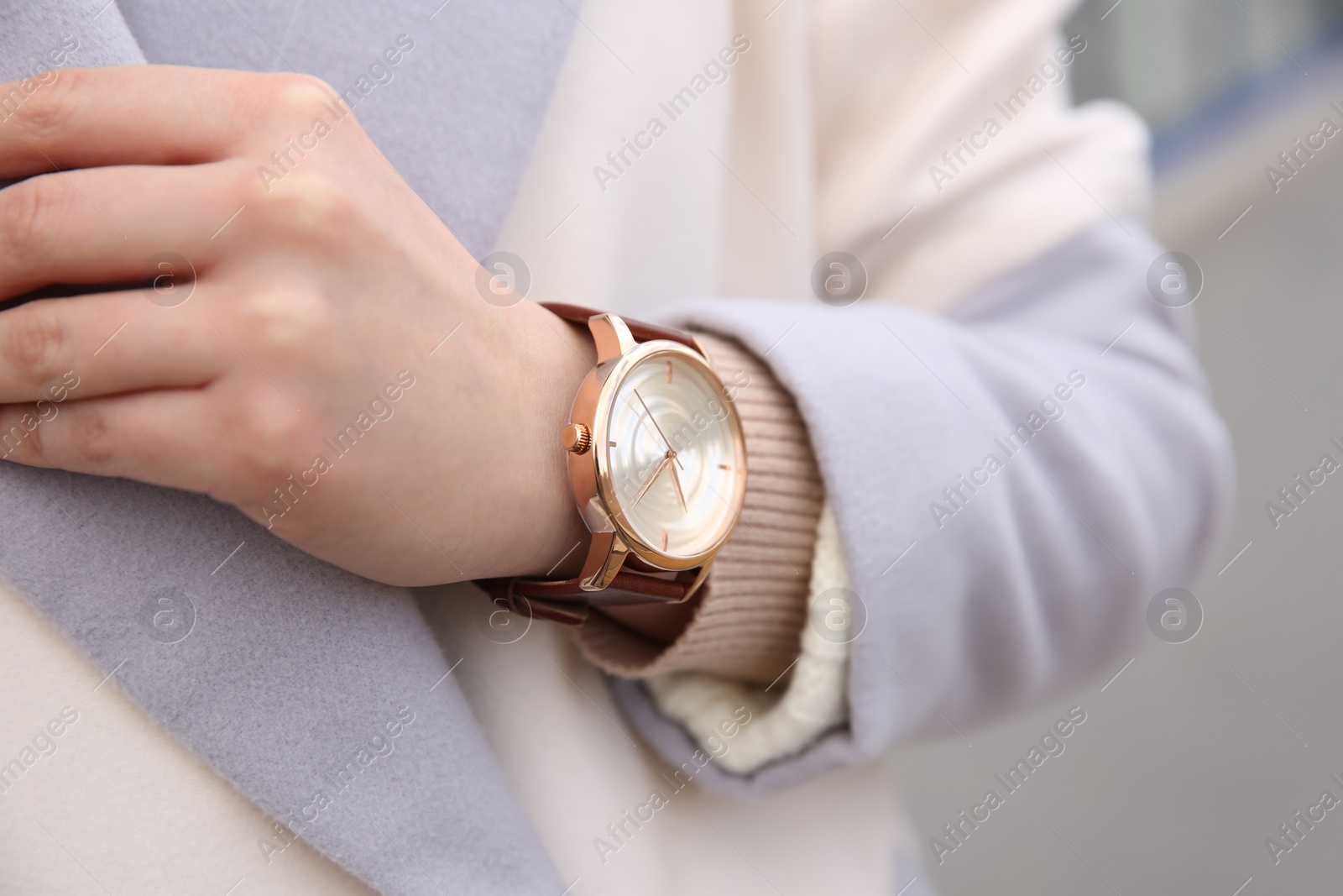 Photo of Woman with luxury wristwatch on blurred background, closeup