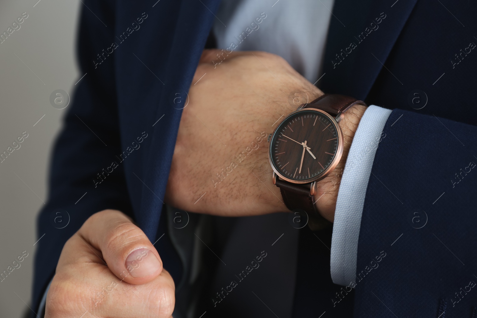 Photo of Businessman with luxury wrist watch on grey background, closeup