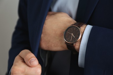 Businessman with luxury wrist watch on grey background, closeup