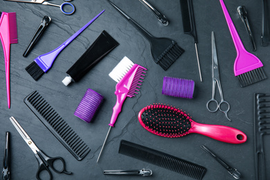 Photo of Professional tools for hair dyeing on black stone background, flat lay