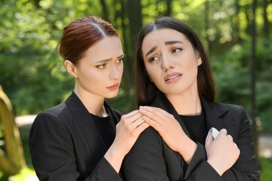 Photo of Sad women in black clothes mourning outdoors. Funeral ceremony