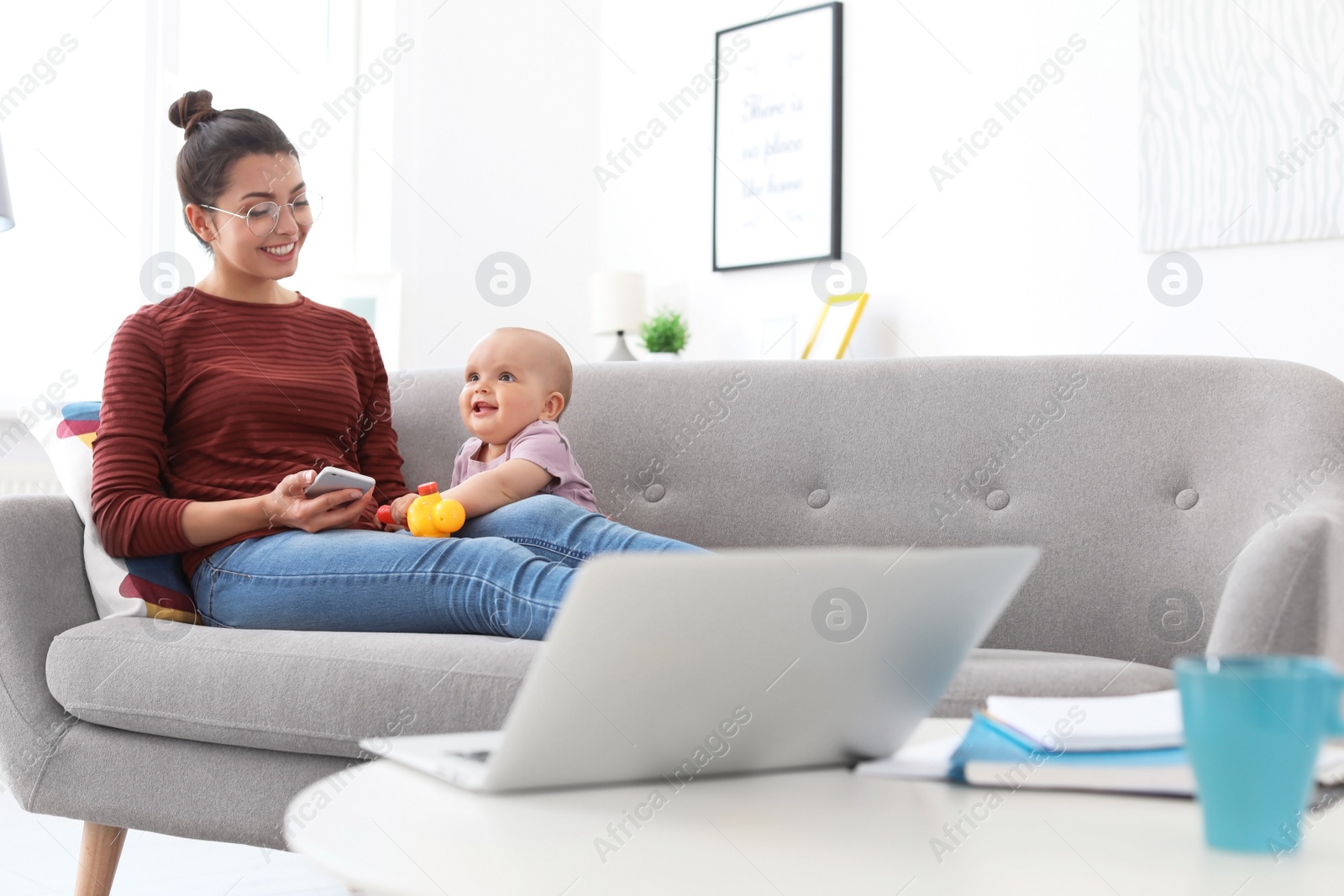 Photo of Young mother with her cute baby girl working at home