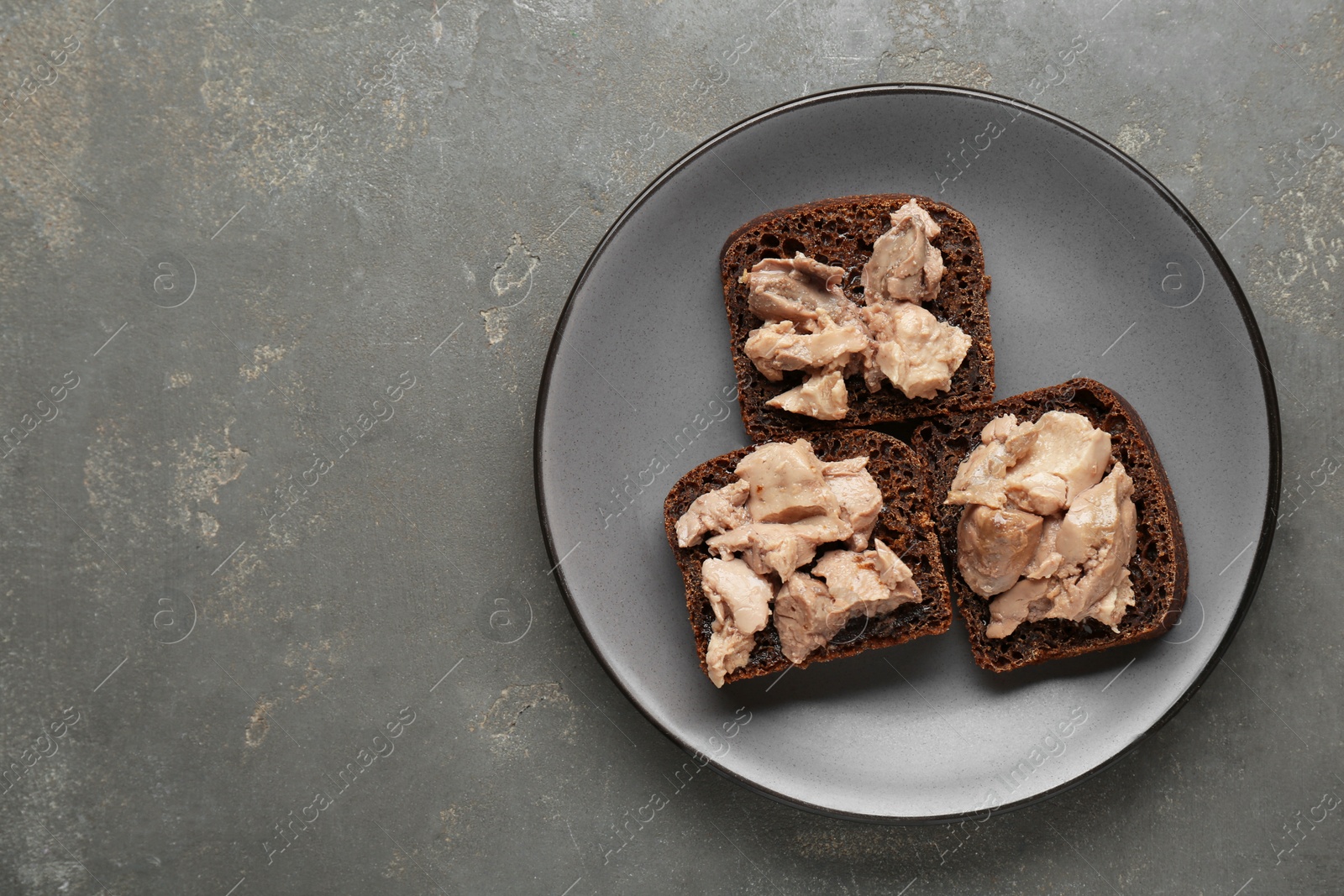 Photo of Tasty sandwiches with cod liver on grey table, top view. Space for text