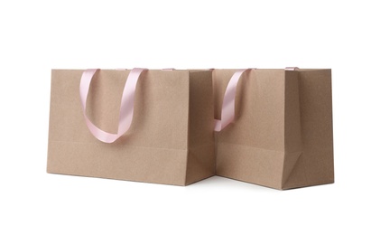 Paper shopping bags with ribbon handles on white background. Mockup for design