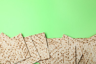 Photo of Traditional matzos on green background, flat lay. Space for text