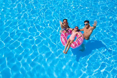 Image of Happy family with inflatable ring in swimming pool. Summer vacation