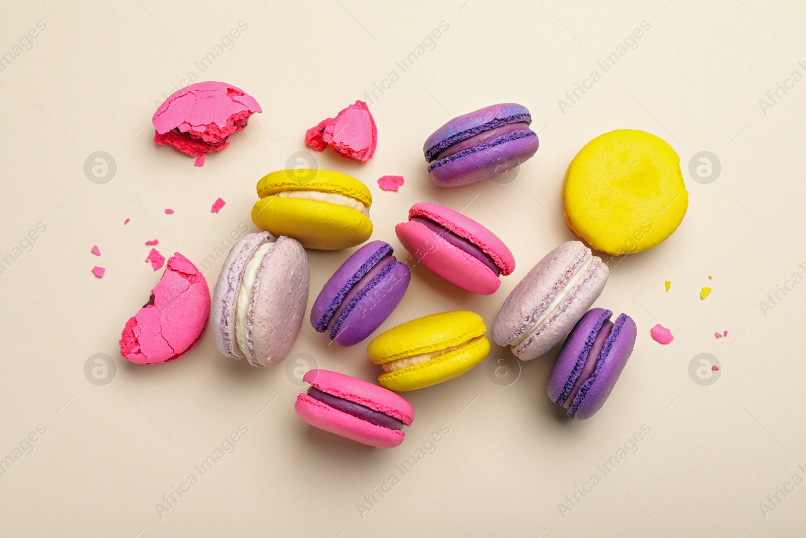 Photo of Delicious colorful macarons on beige background, flat lay