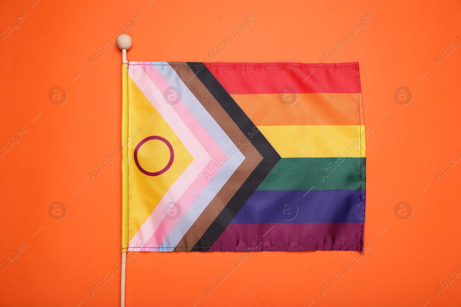 Photo of Bright progress flag on orange background, top view. LGBT pride