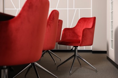 Photo of Stylish red office chairs and large table in empty conference room