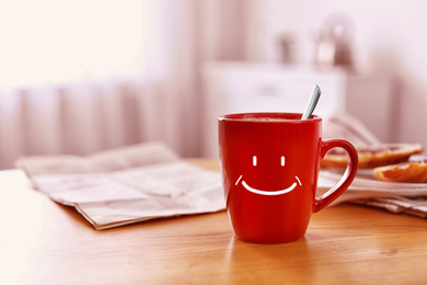 Image of Aromatic coffee in cup with happy face on wooden table indoors, space for text. Good morning