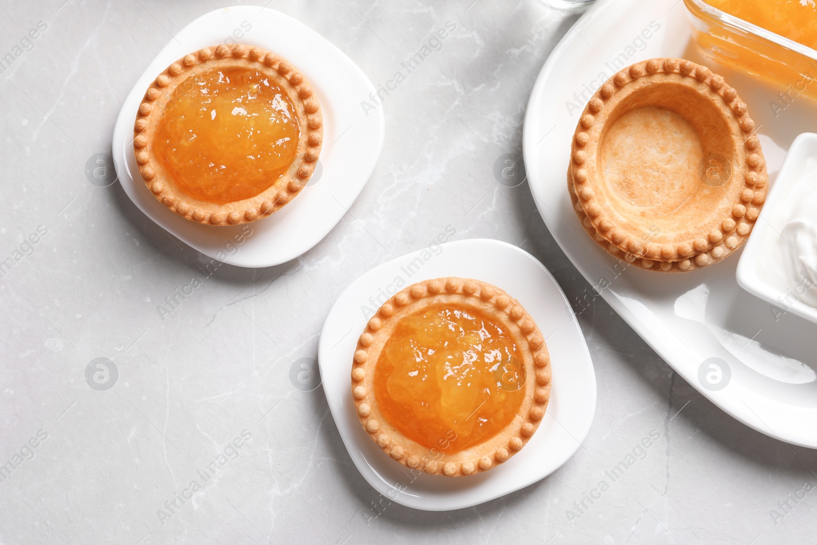 Photo of Tasty tartlets with jam on light background, top view