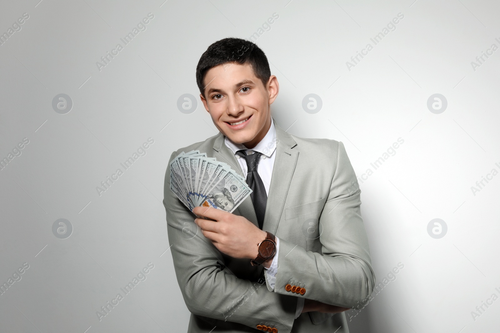 Photo of Portrait of young businessman with money fan on light background