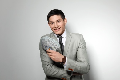 Portrait of young businessman with money fan on light background