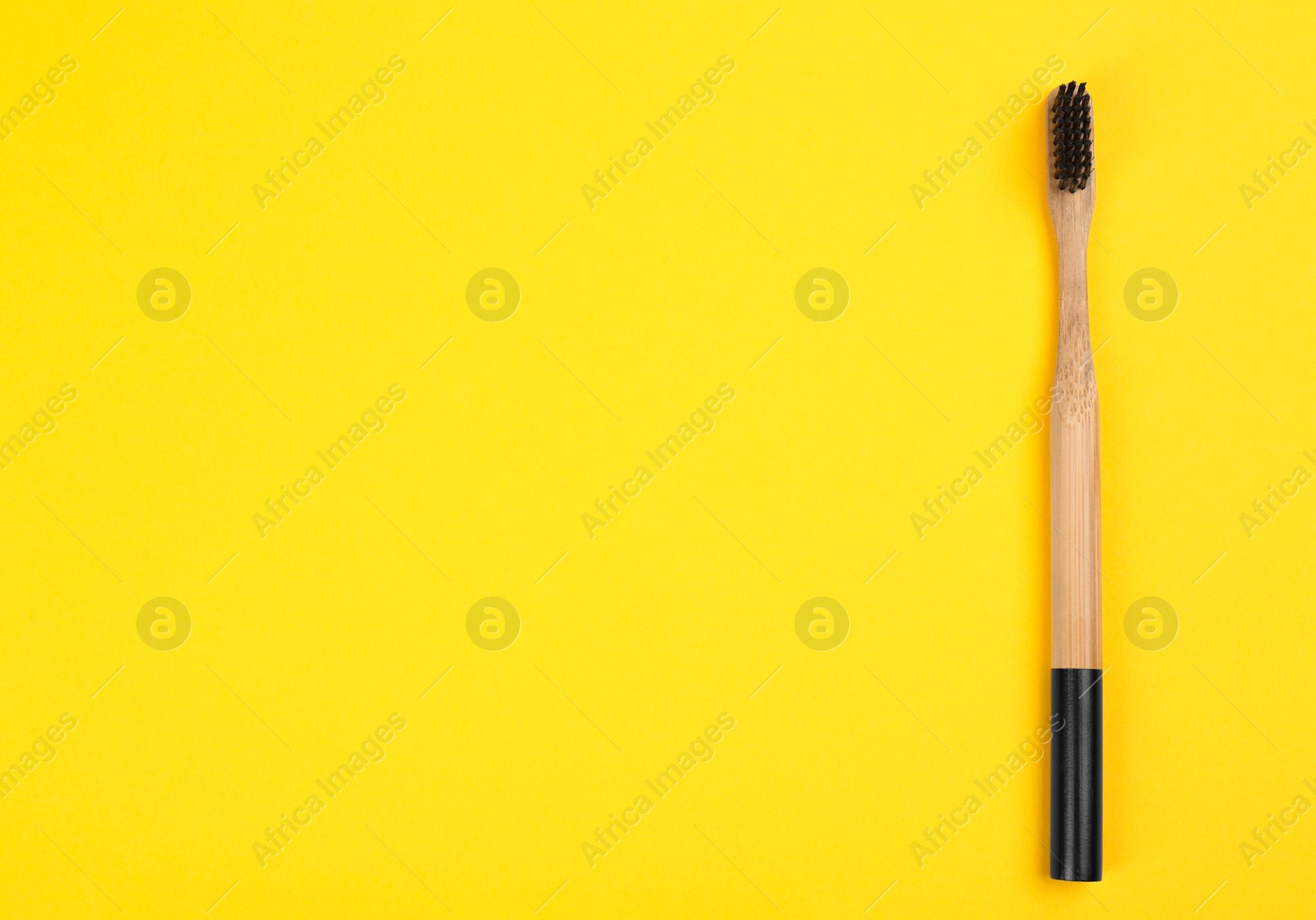 Photo of Toothbrush made of bamboo on yellow background, top view. Space for text