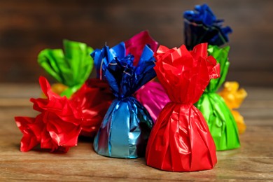 Candies in colorful wrappers on wooden table, closeup