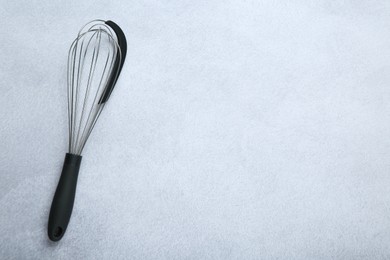Metal whisk on gray table, top view. Space for text