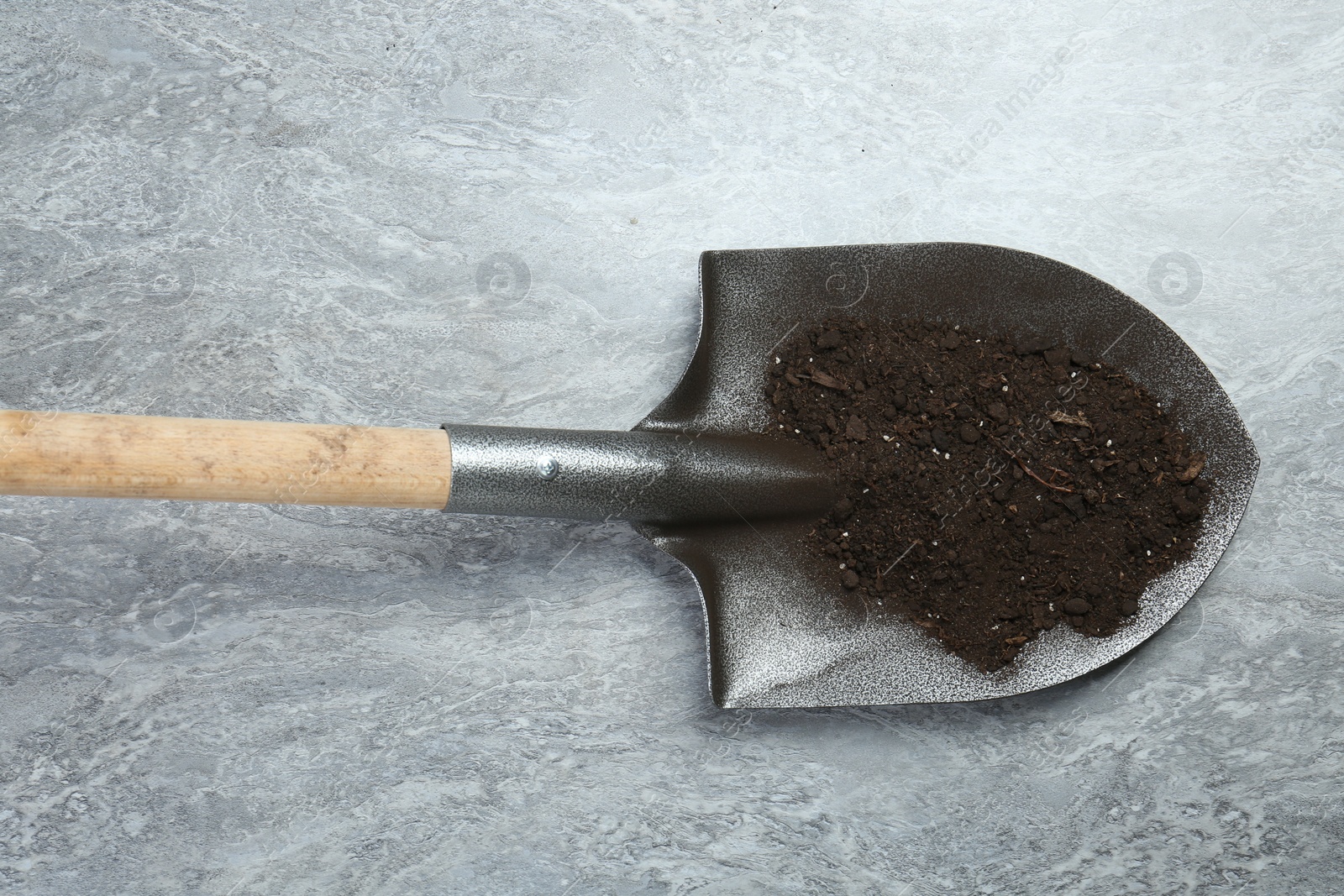 Metal shovel with fertile soil on gray textured surface, top view Photo of Metal shovel with fertile soil on gray textured surface, top view