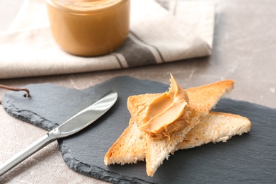 Photo of Tasty toasts with peanut butter on slate plate