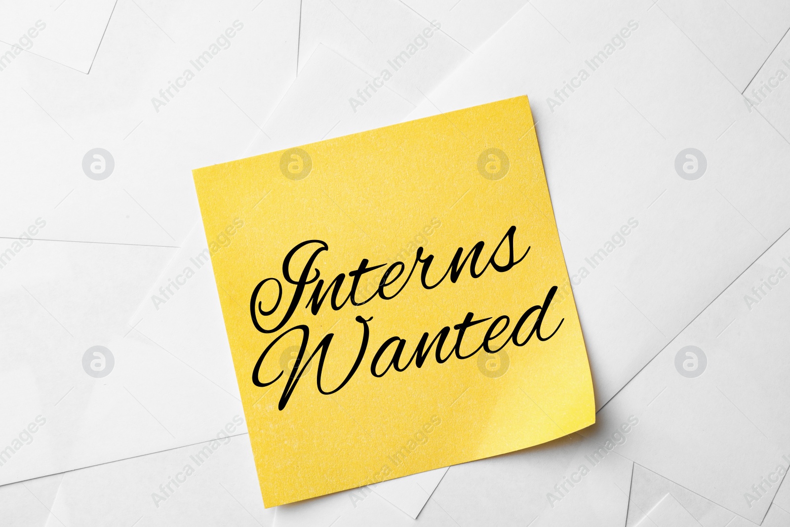 Image of Note with text INTERNS WANTED on paper sheets, top view