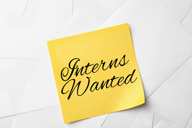 Note with text INTERNS WANTED on paper sheets, top view