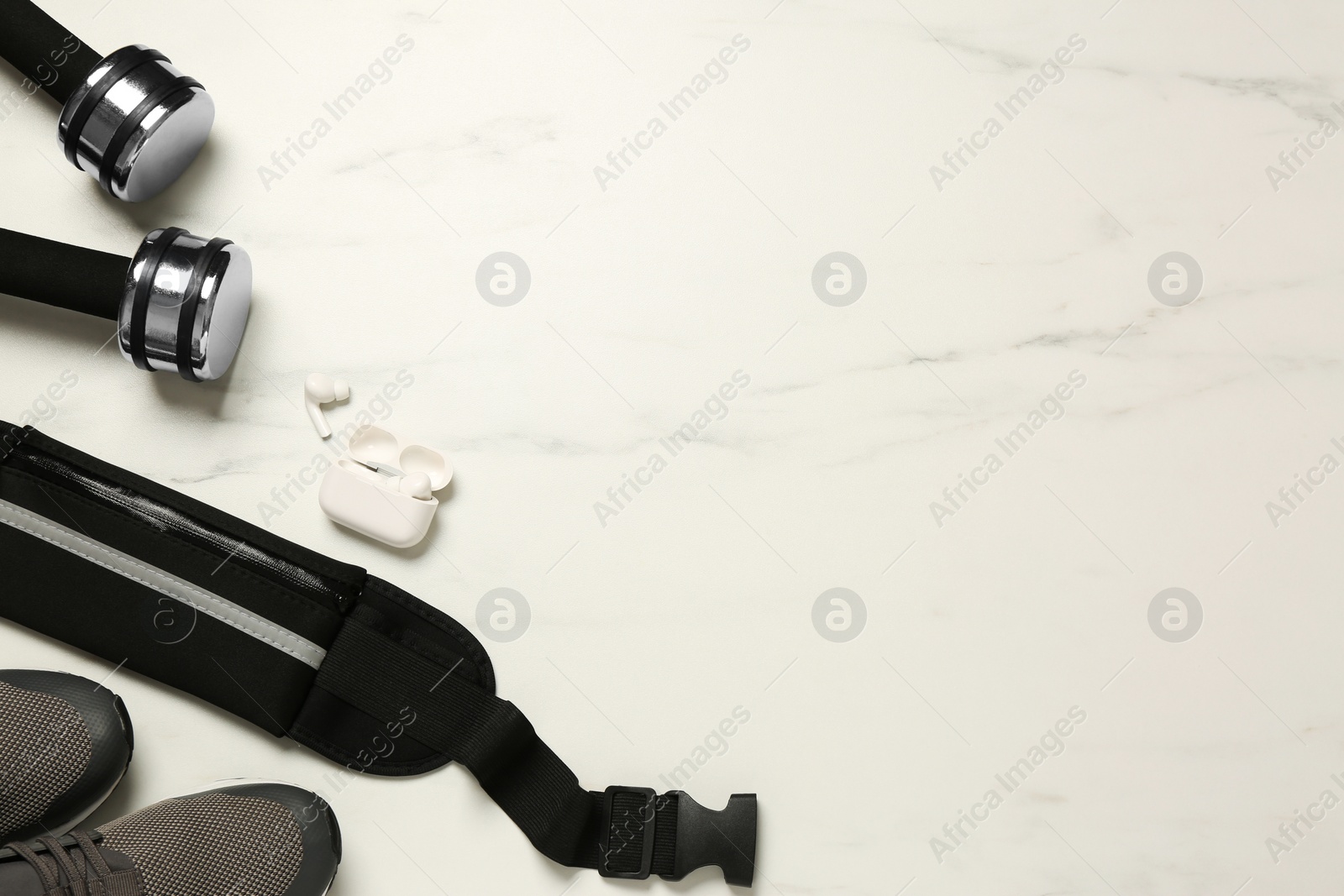 Photo of Flat lay composition with black waist bag on white marble table, space for text