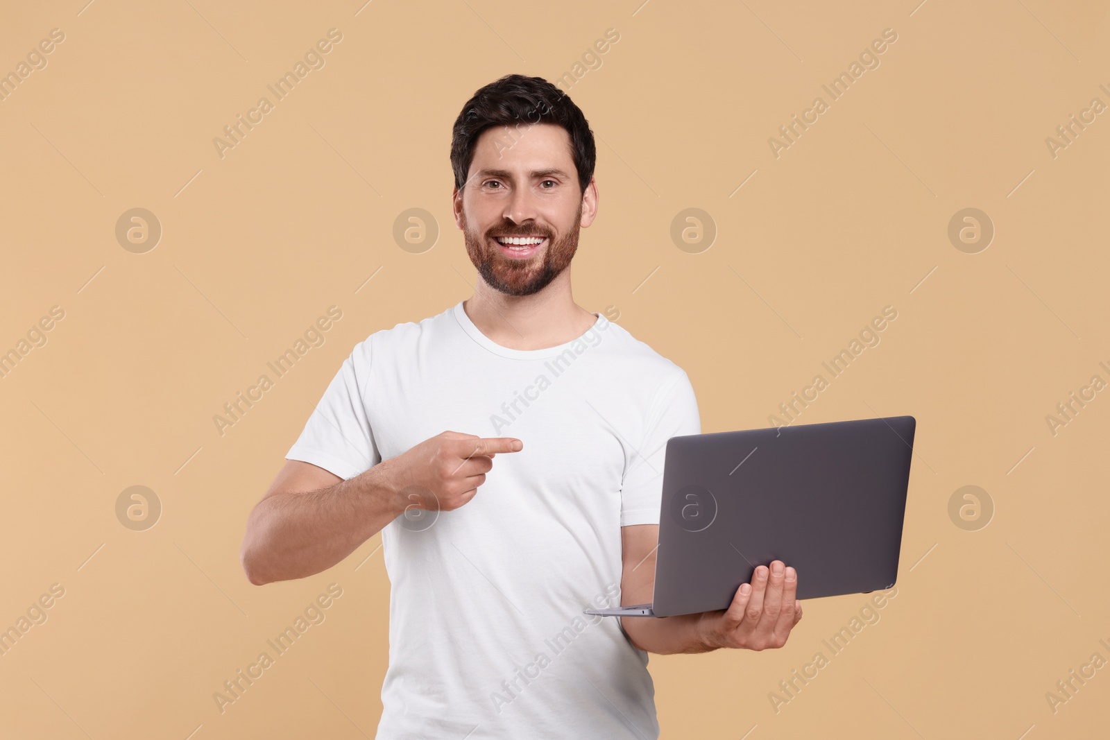 Photo of Happy man with laptop on beige background